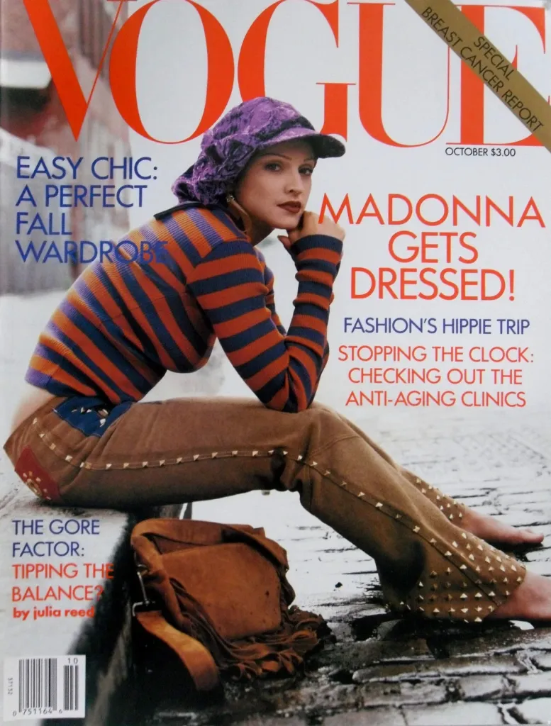 Madonna on the cover of Vogue magazine in a purple cap and a striped shirt with brown studded pants.