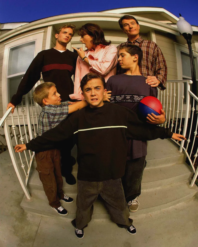 Cast shot of the Malcolm in the Middle family on a front porch.