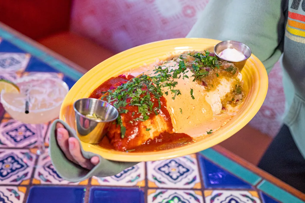Margs El Jefe Burrito with sauces and cilantro, served with a margarita.