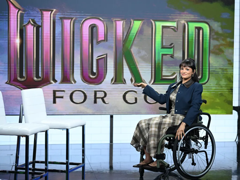 Marissa Bode in a wheelchair, gesturing with one hand in front of a 