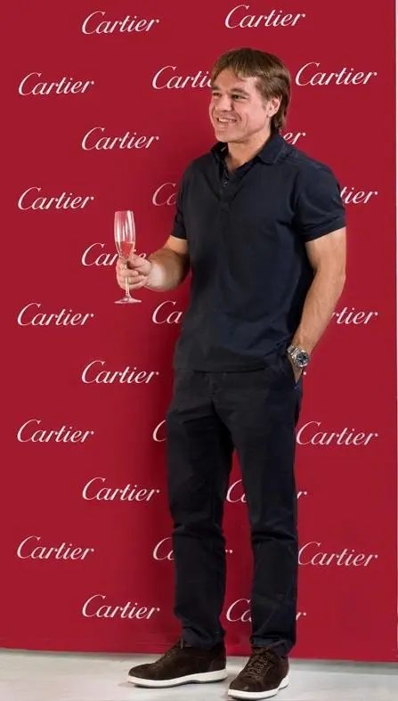 Maximilien de Hoop Cartier holding a glass of champagne in front of a red Cartier-branded backdrop.