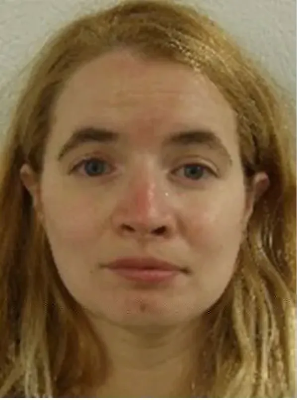 Booking photo of a woman with long, light brown hair, looking directly at the camera.