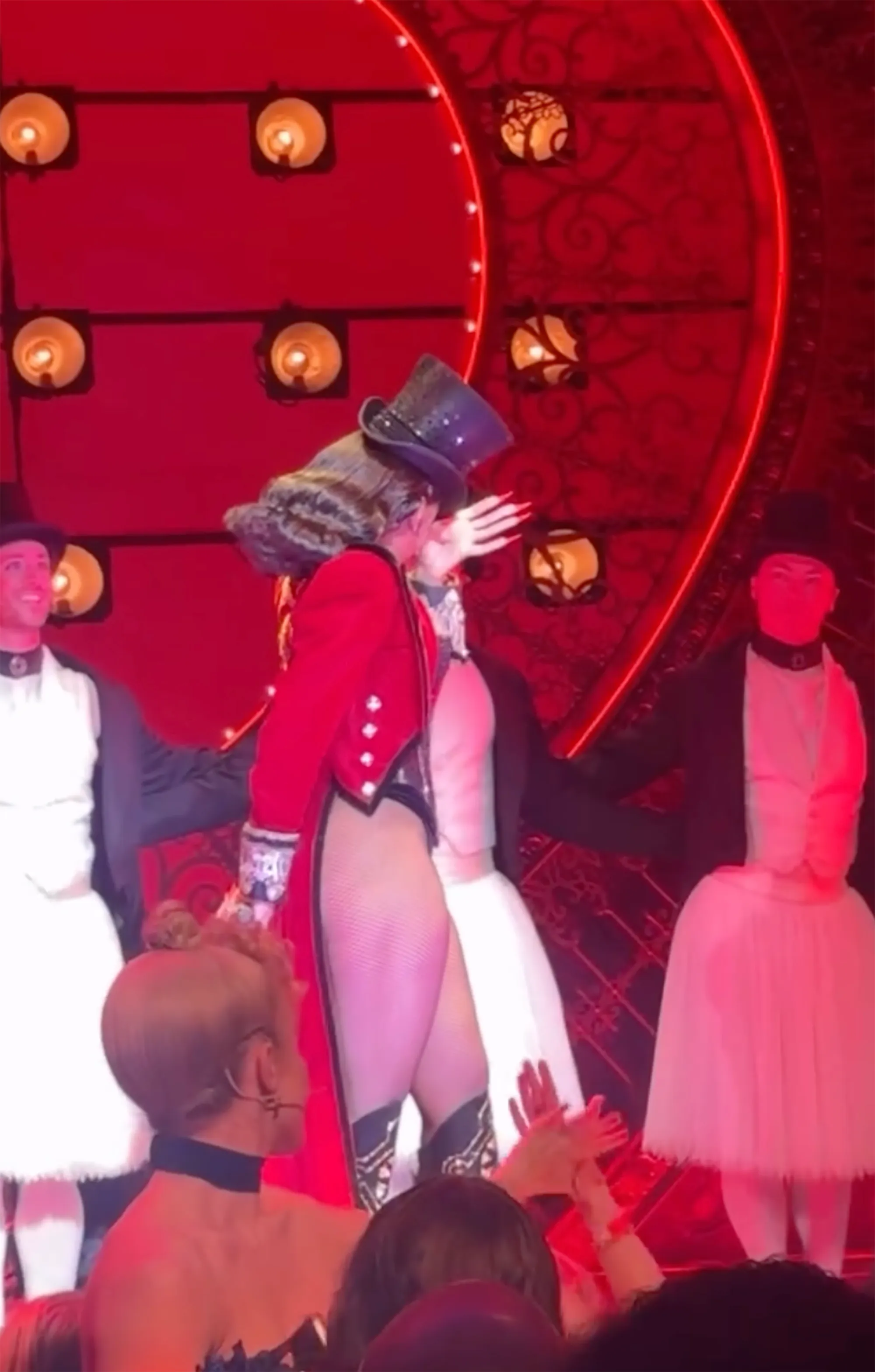 Megan Thee Stallion in a black top hat and red coat, wiping away tears on stage while performing as Zidler in 