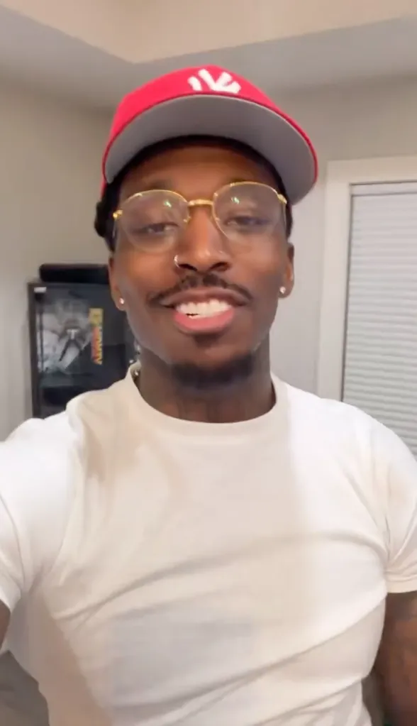 Pardison Fontaine smiling in a red baseball cap and glasses.