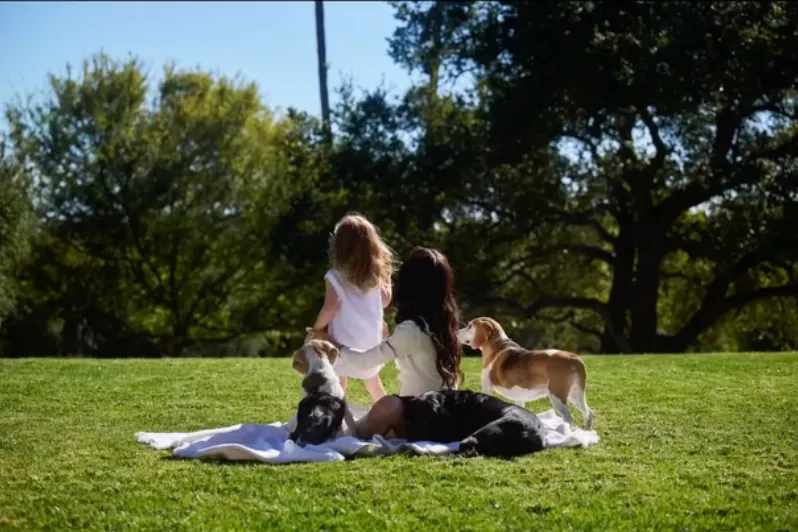 Meghan Markle, Lilibet, and dogs Guy and Mia in a grassy field.