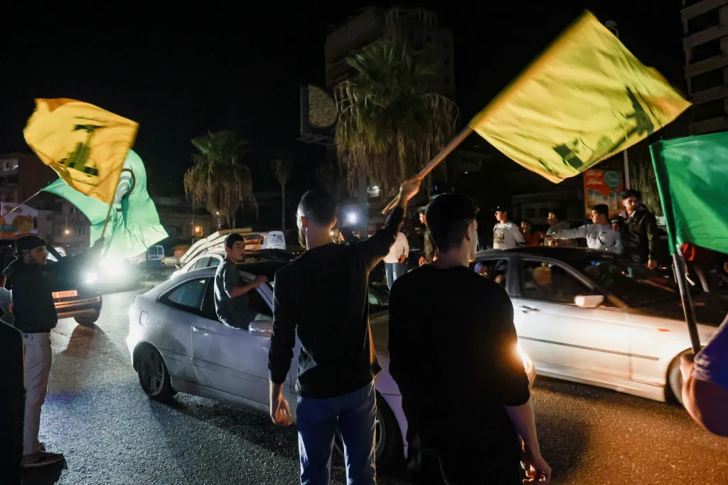 Men waving flags as displaced people return to their homes after a 10-day ceasefire between Lebanon and Israel went into effect in Sidon.