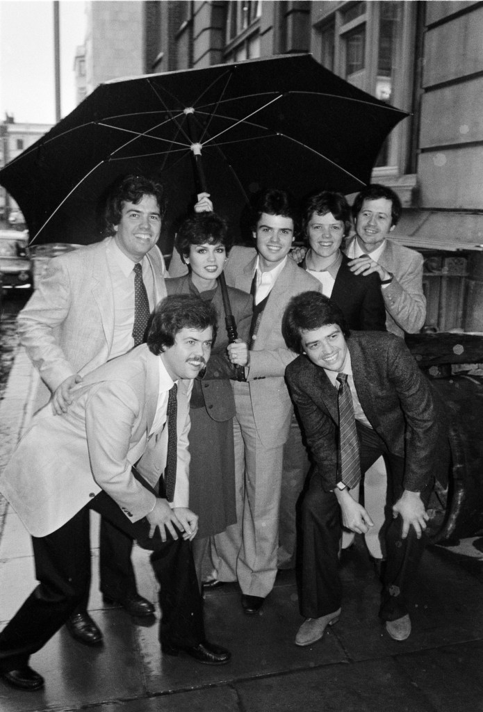 The Osmonds posing under an umbrella in London.