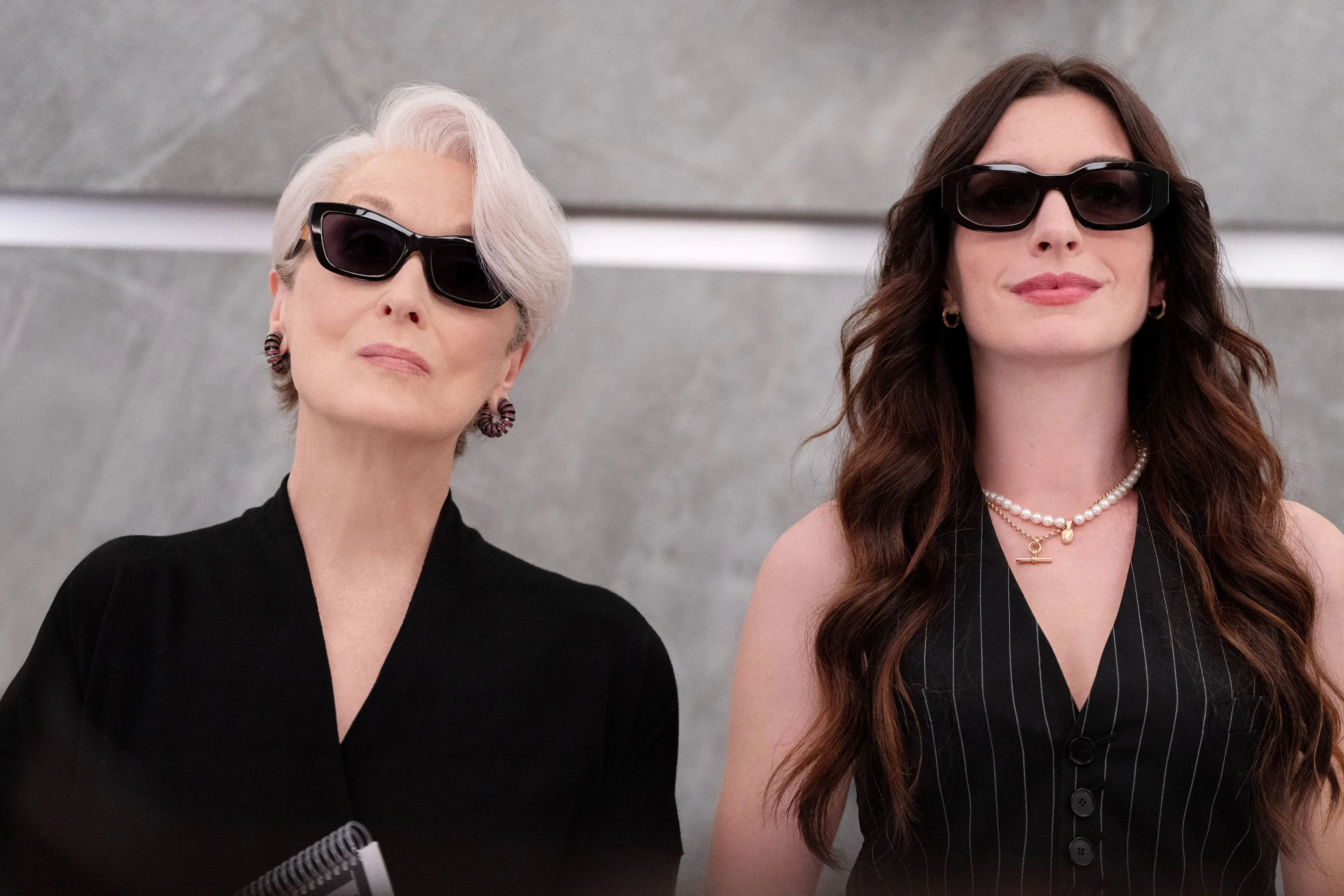 Meryl Streep and Anne Hathaway in sunglasses, looking forward.