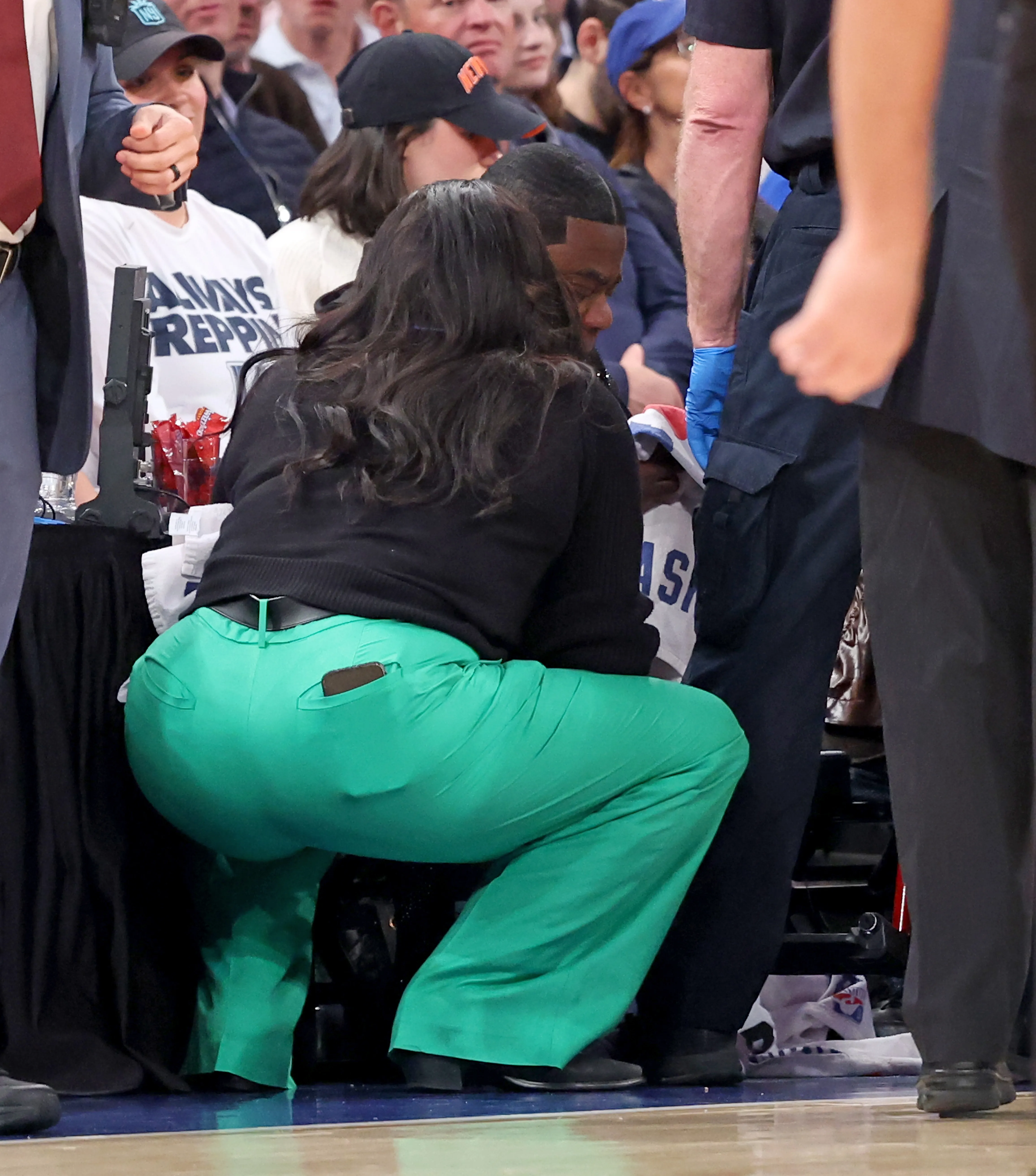 Tracy Morgan being checked on by a woman in green pants after he threw up on the court during a Miami Heat vs. New York Knicks game at Madison Square Garden.