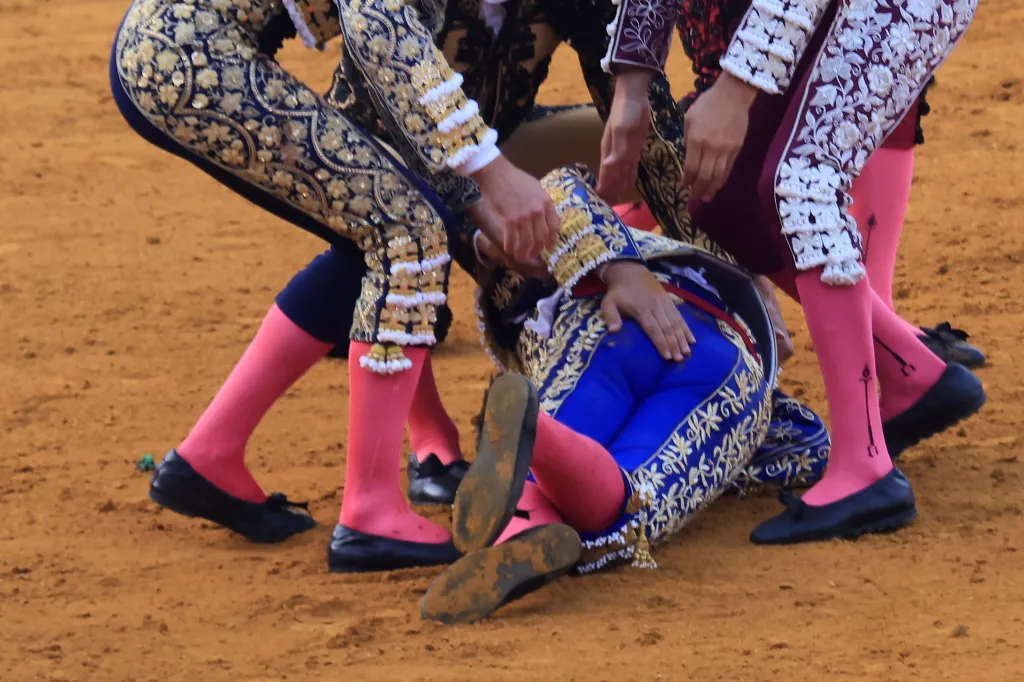 Morante de la Puebla on the ground with other bullfighters attending to him after his injury. 