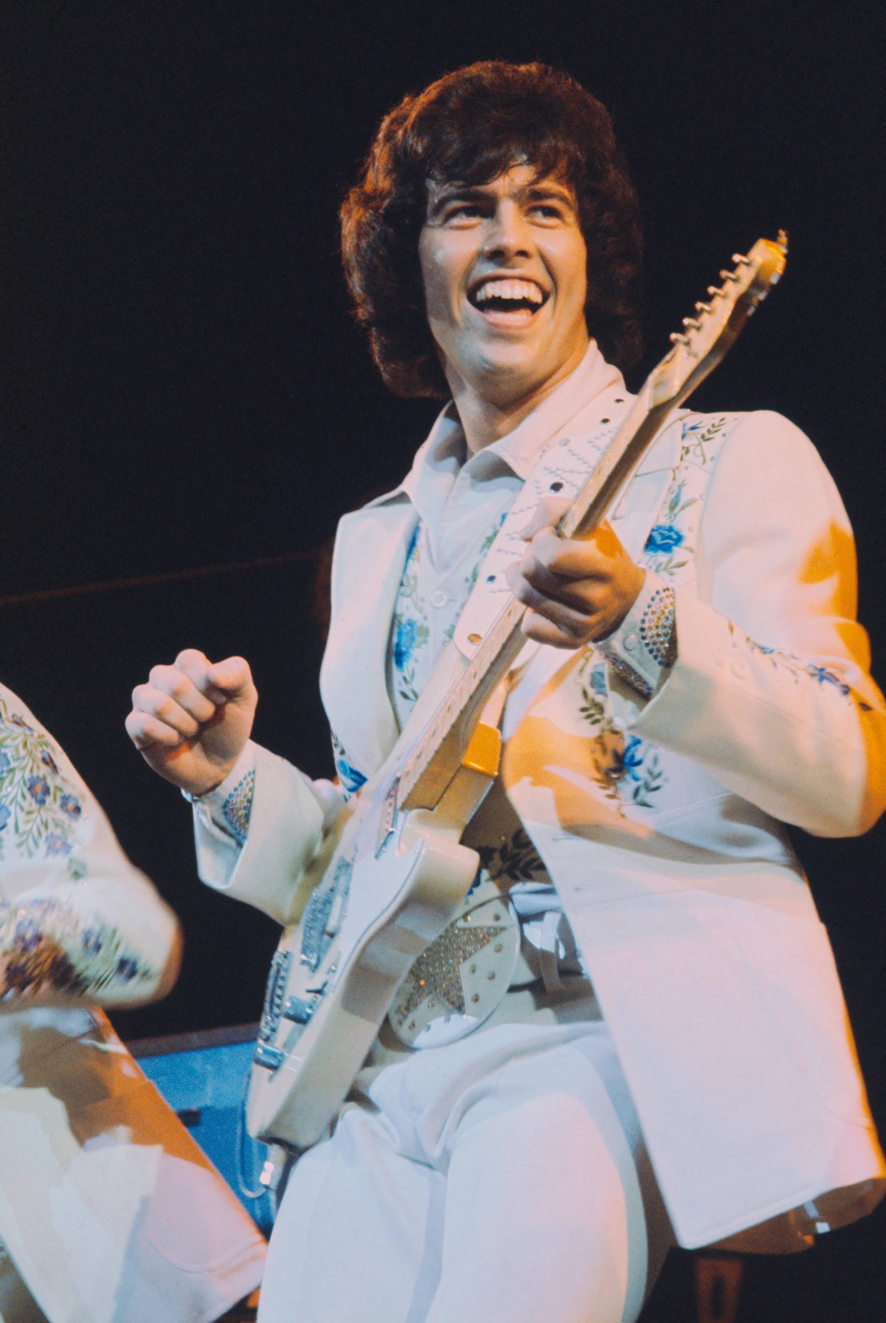 Alan Osmond performing live with his guitar on stage.
