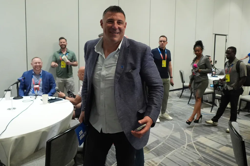 New England Patriots head coach Mike Vrabel carrying the Joe Brady name placard.