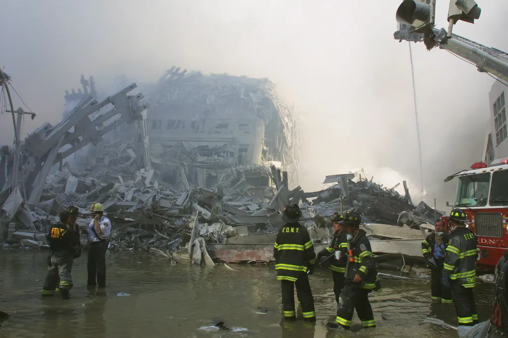 New York City firefighters stand among the rubble and smoke at the World Trade Center site.