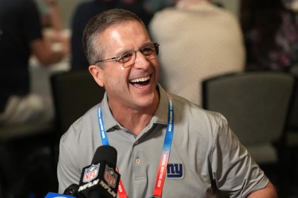 New York Giants head coach John Harbaugh laughs during an interview.