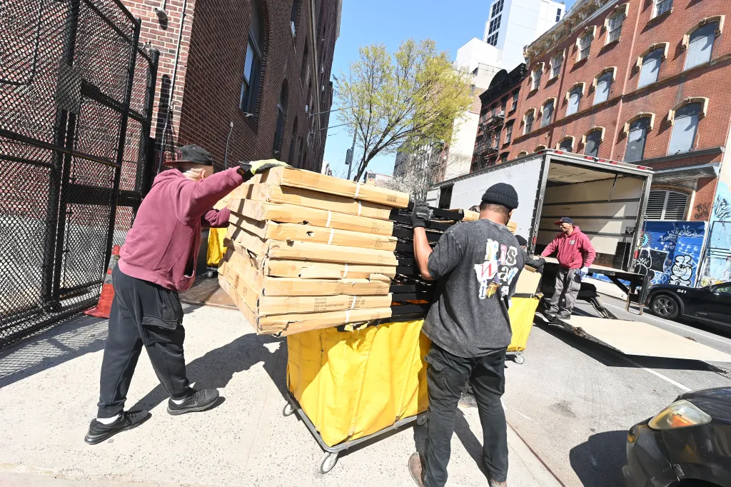 Workers move cots from a shelter to a truck on East 3rd Street.