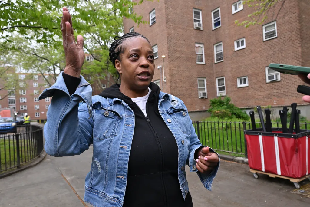 Woodside Houses resident Jennifer Lambert gestures while speaking outdoors.