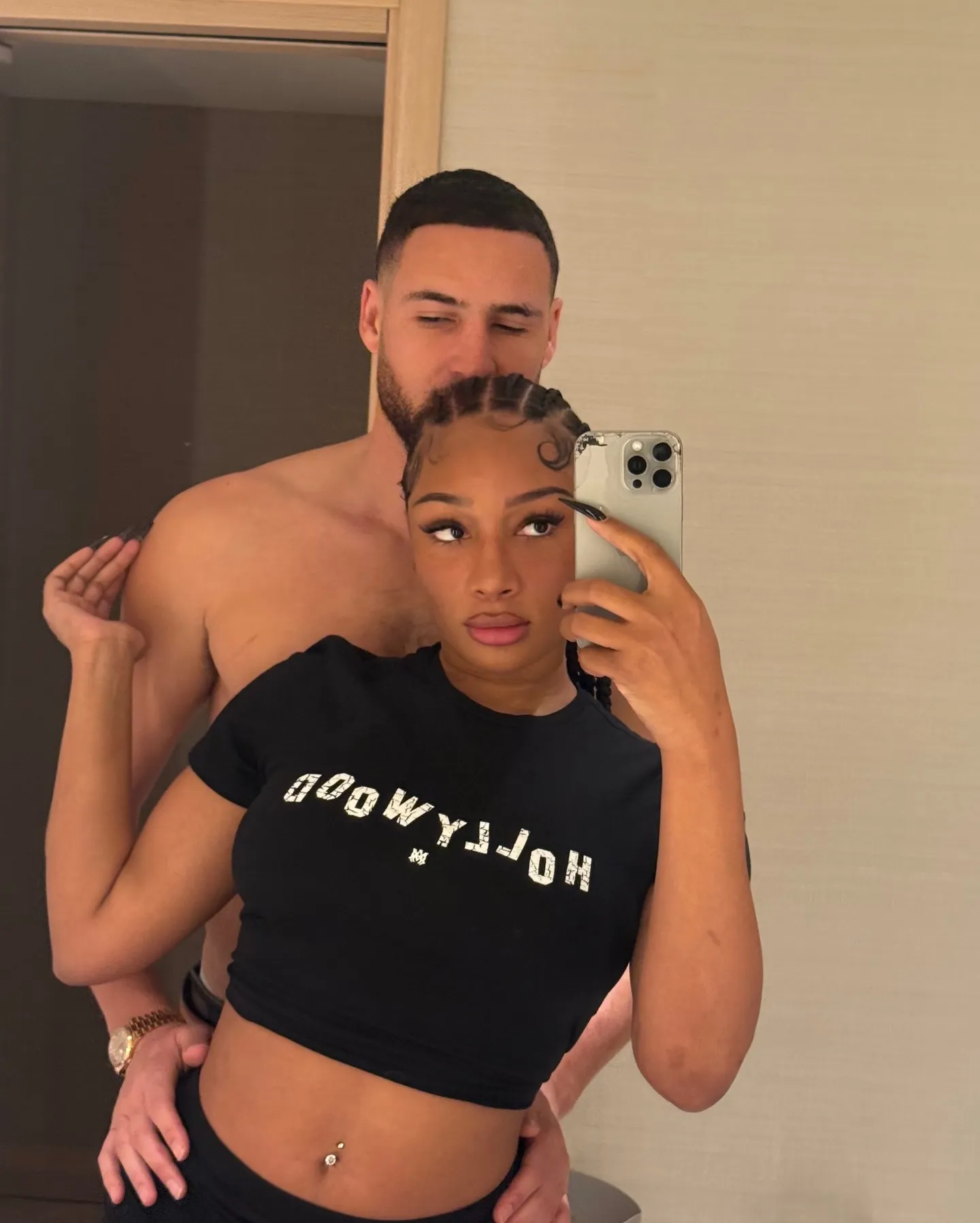 Megan Thee Stallion taking a mirror selfie with Klay Thompson behind her.
