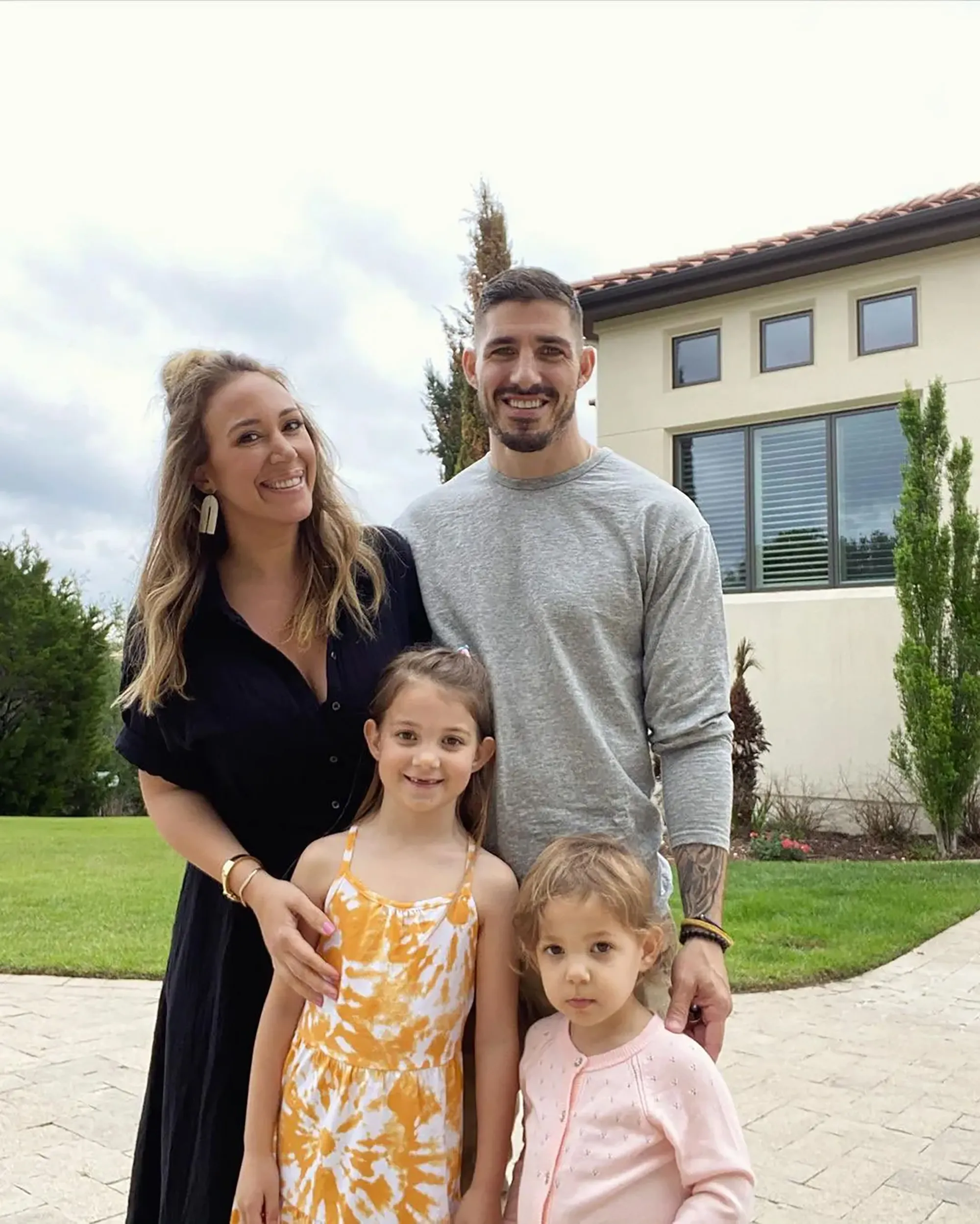 Haylie Duff and Matt Rosenberg pose with their two daughters, who are wearing a yellow and white dress and a pink sweater.