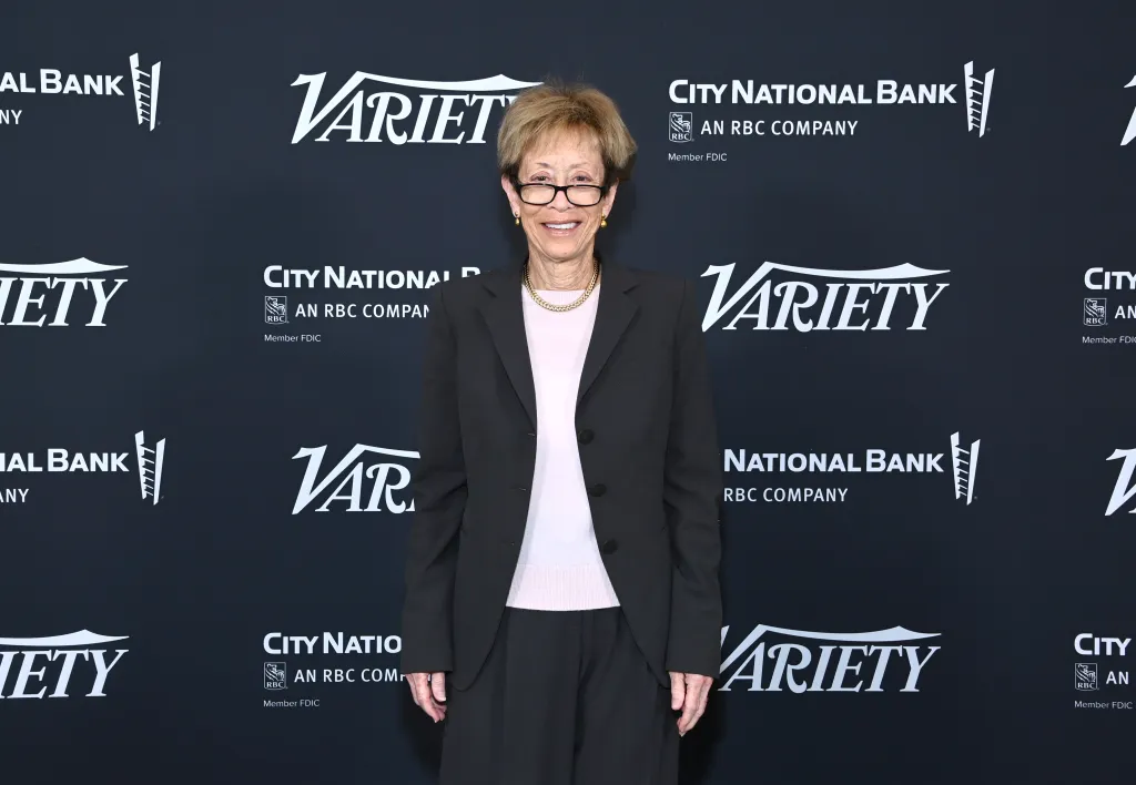 Patricia L. Glaser, Partner and Chair of Litigation Department at Glaser Weil, smiling in a black suit and light pink shirt in front of a backdrop with 