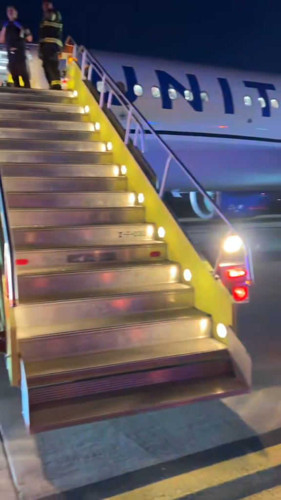 Emergency crew members on stairs leading to a United Airlines plane after a bomb threat.