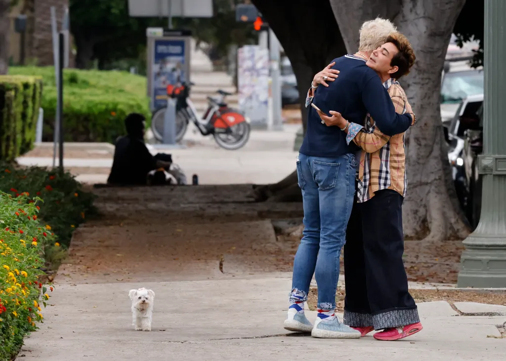 Patrik Simpson and Pol Atteu hug outside LAPD Hollywood Station after filing a police report.