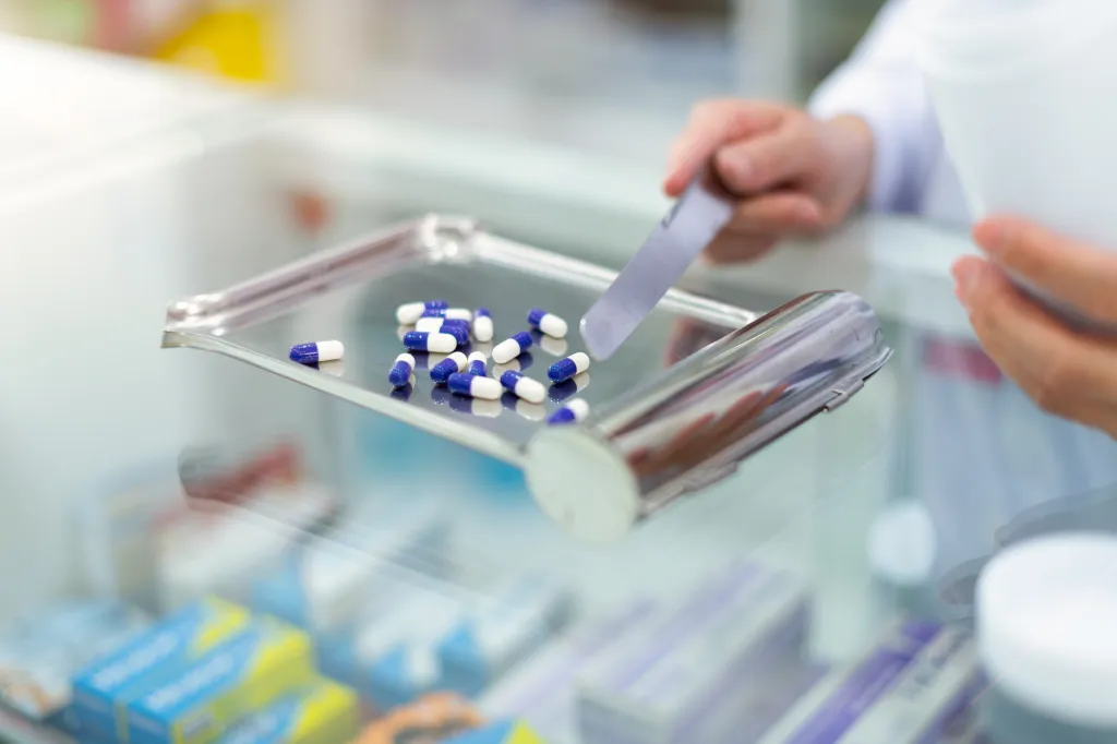 Pharmacist counting pills on a counting tray.