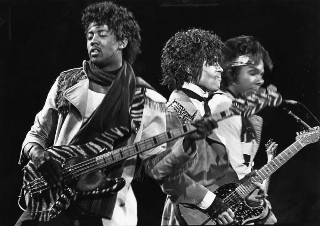 Mark Brown, Prince, and Dez Dickerson on stage performing.