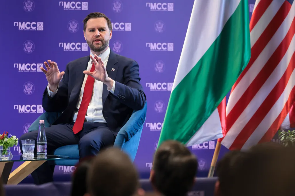 US Vice President JD Vance speaking at the Mathias Corvinus Collegium in Budapest, with the Hungarian and US flags visible.