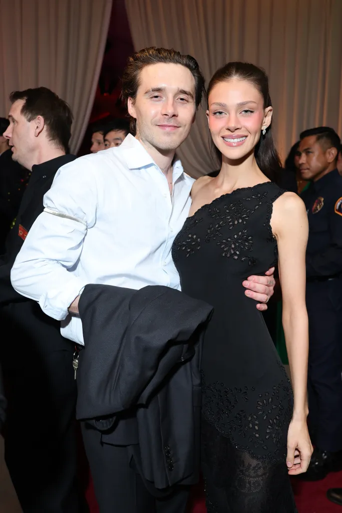 Brooklyn Peltz Beckham, in a white shirt, and Nicola Peltz Beckham, in a one-shouldered black dress, attending an event.