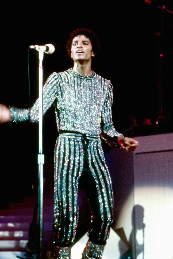 Michael Jackson performing on stage in a sparkly silver and black striped outfit.