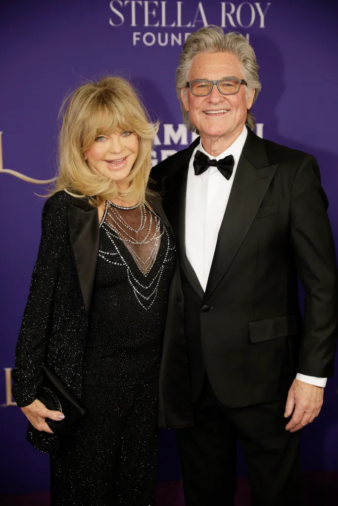 Goldie Hawn in a black sparkly dress and Kurt Russell in a black tuxedo smile at COSF's 4th Annual Aspen Snow Ball Gala.