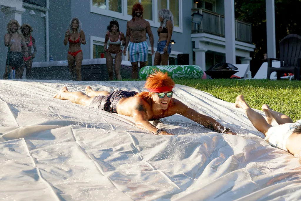 Luke Gulbranson on a slip-and-slide while other people watch.