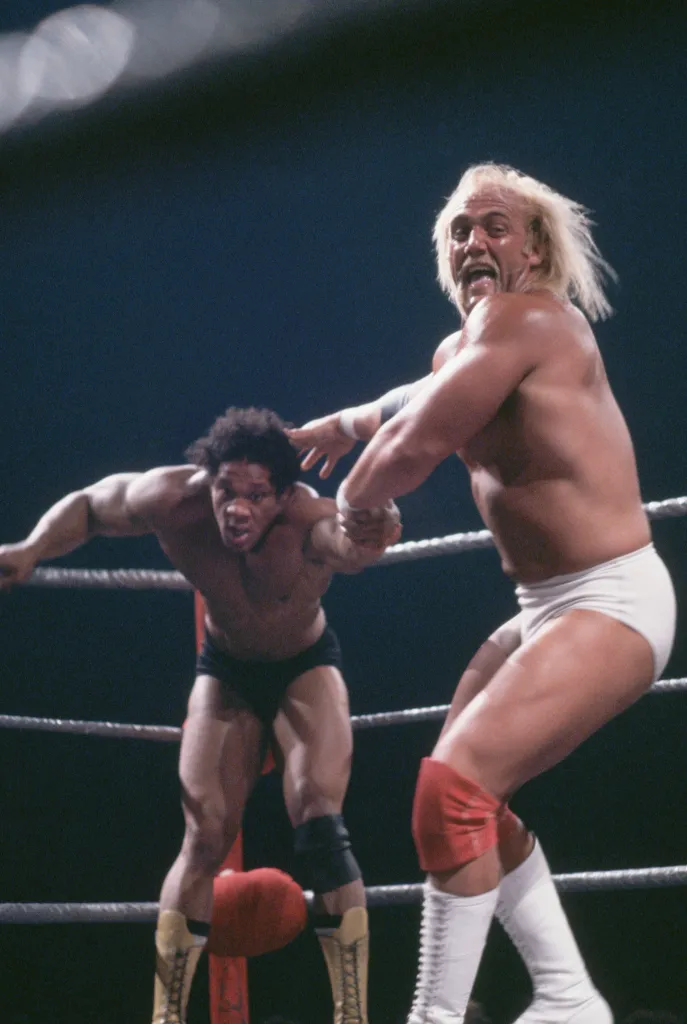 Hulk Hogan throwing Tony Atlas in a wrestling ring.