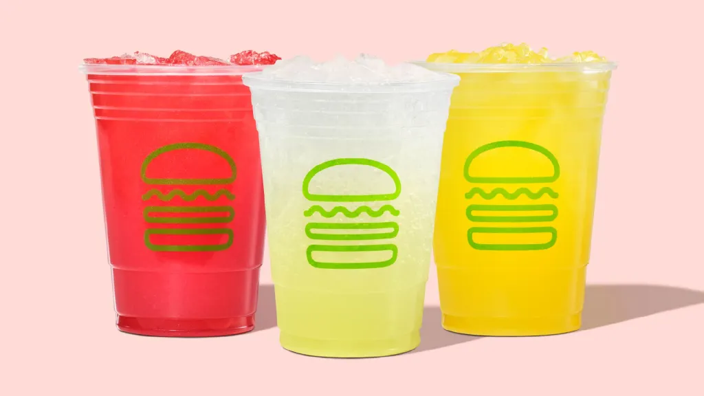 Three Shake Shack beverages: a red drink, a clear drink, and a yellow drink, each with ice and the Shake Shack burger logo.