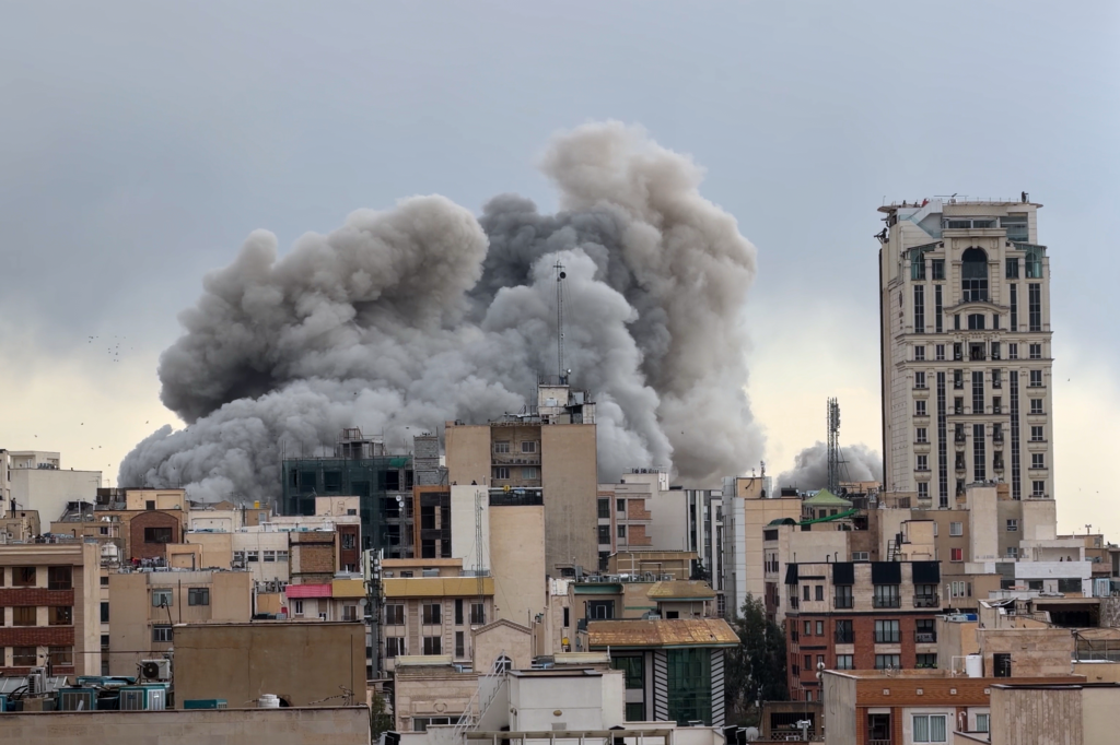 A plume of smoke rises above buildings in Tehran, Iran, after a strike.