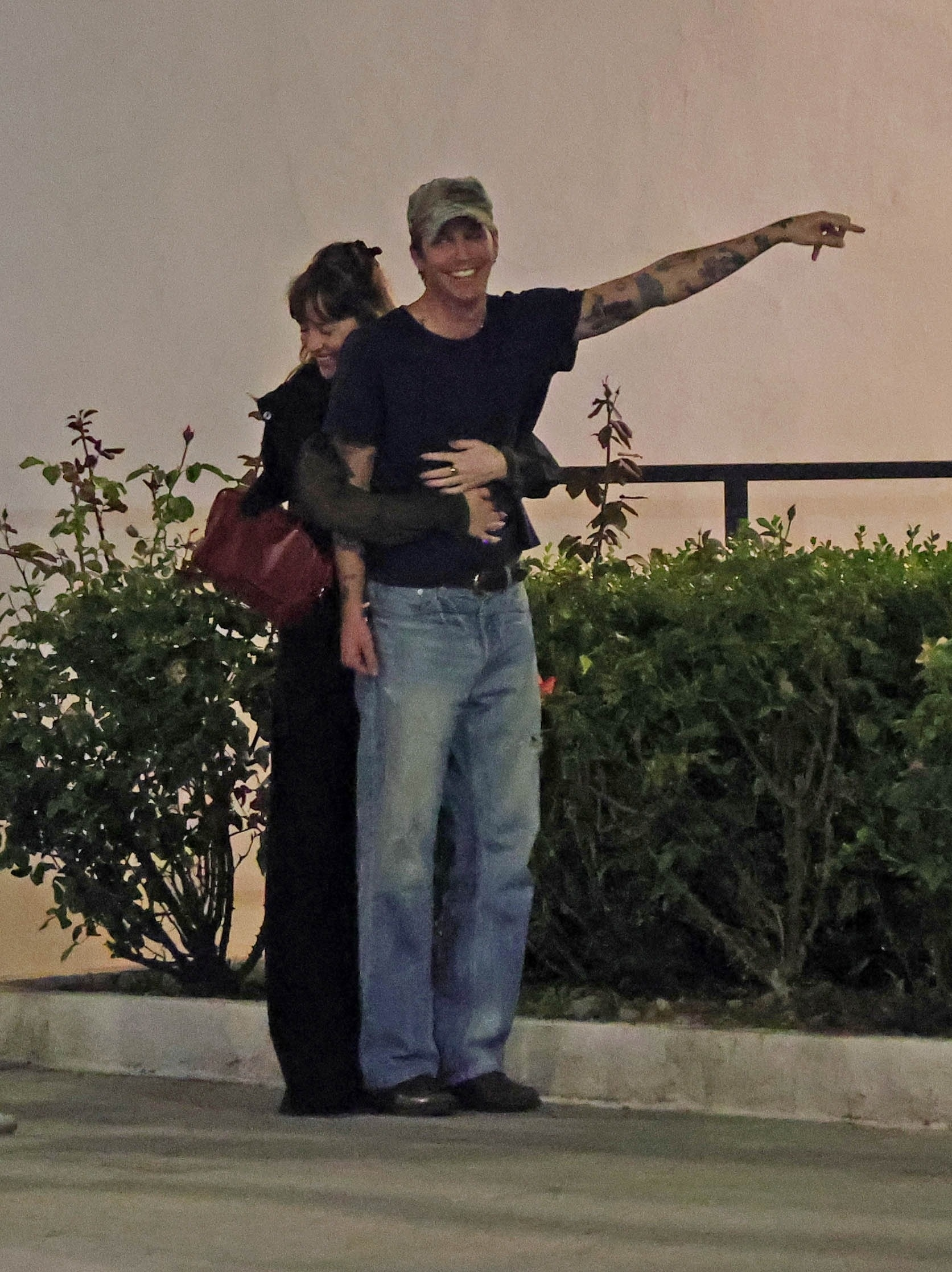 Dakota Johnson hugging Role Model from behind, who is pointing to the right.