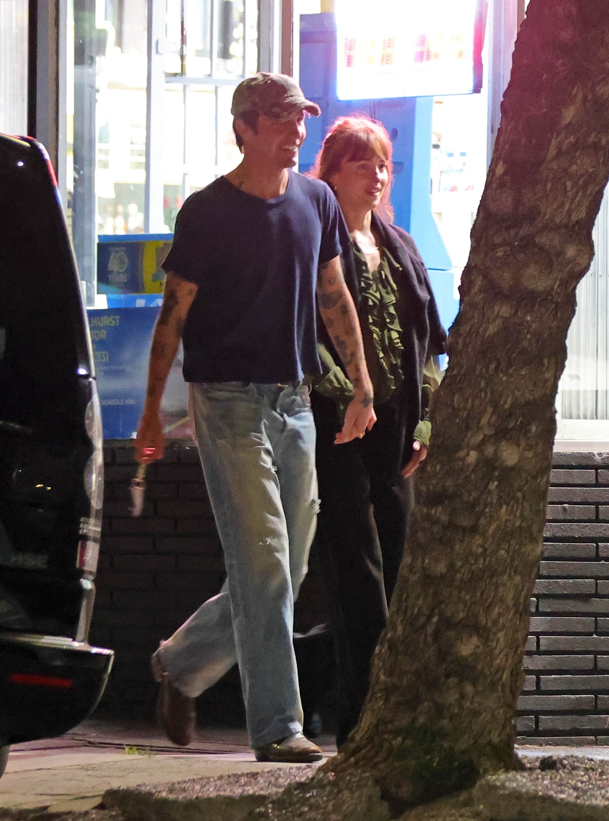 Dakota Johnson and Role Model walking hand-in-hand at night.