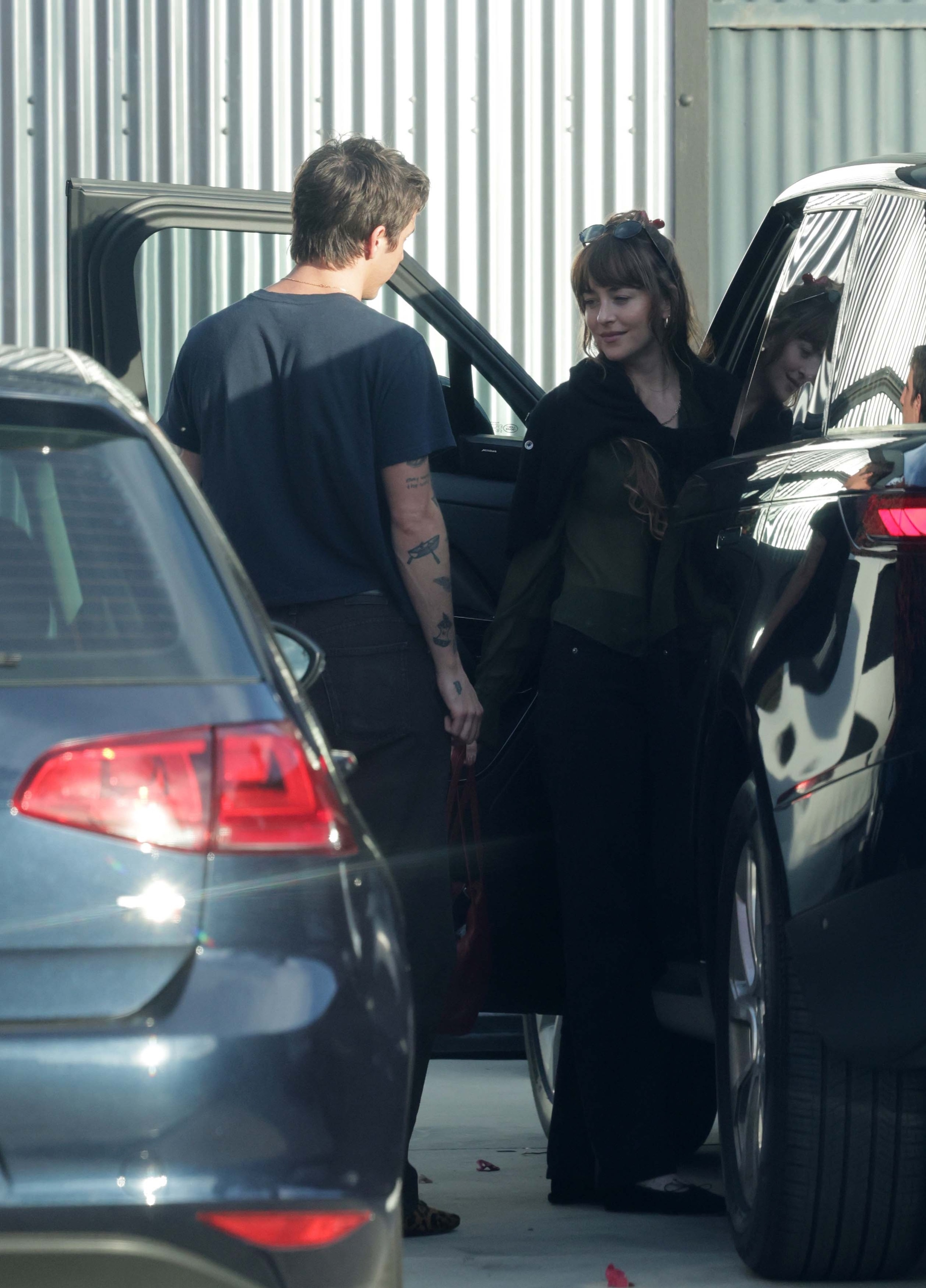 Dakota Johnson and Role Model in a PDA moment while she is getting out of a car.