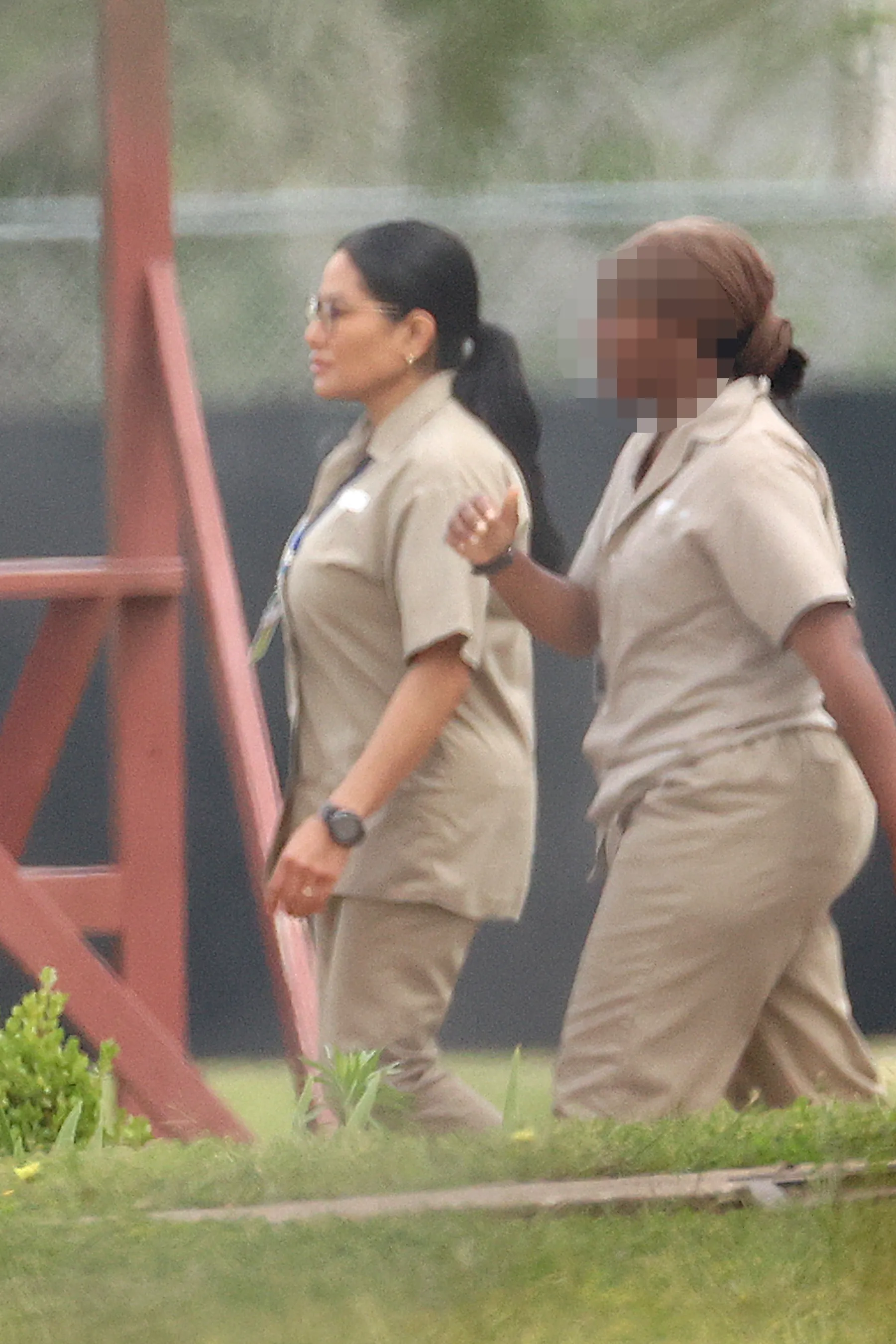 Jen Shah in prison uniform, walking with another inmate, who is blurred.
