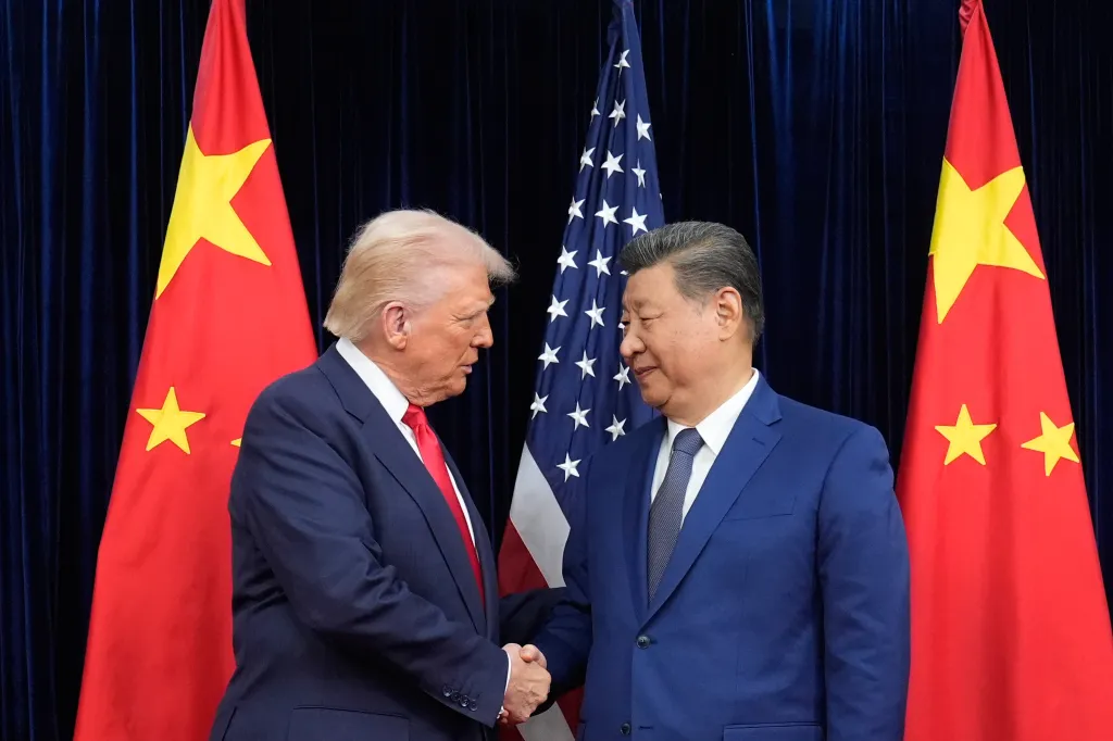 Donald Trump and Xi Jinping shake hands in front of American and Chinese flags.