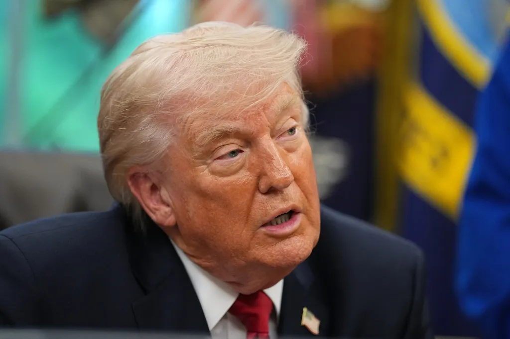 Donald Trump speaking while wearing a suit, white shirt, and red tie.