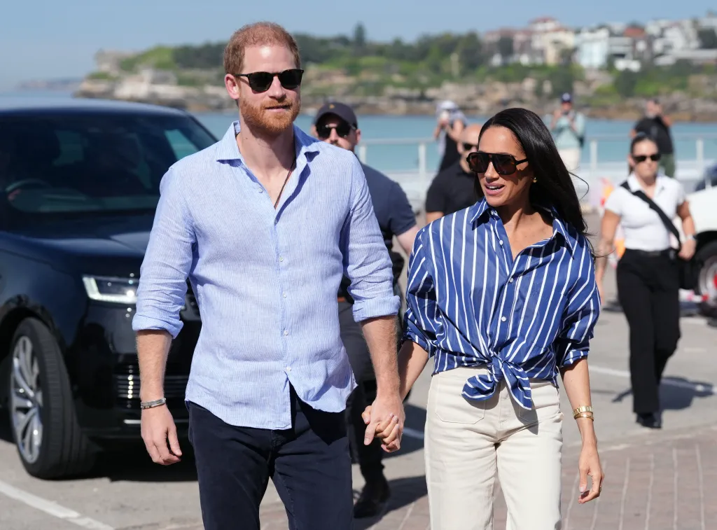Prince Harry and Meghan Markle holding hands at Bondi Beach in Sydney.