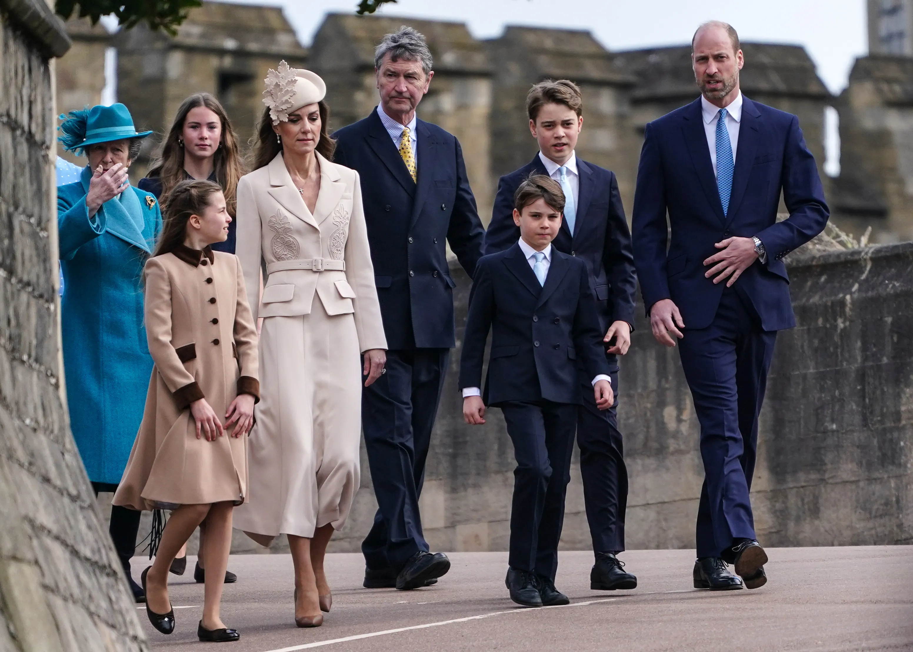 Members of the Royal Family including Princess Charlotte, Catherine Princess of Wales, Prince Louis, Prince George, and Prince William, walk outdoors.