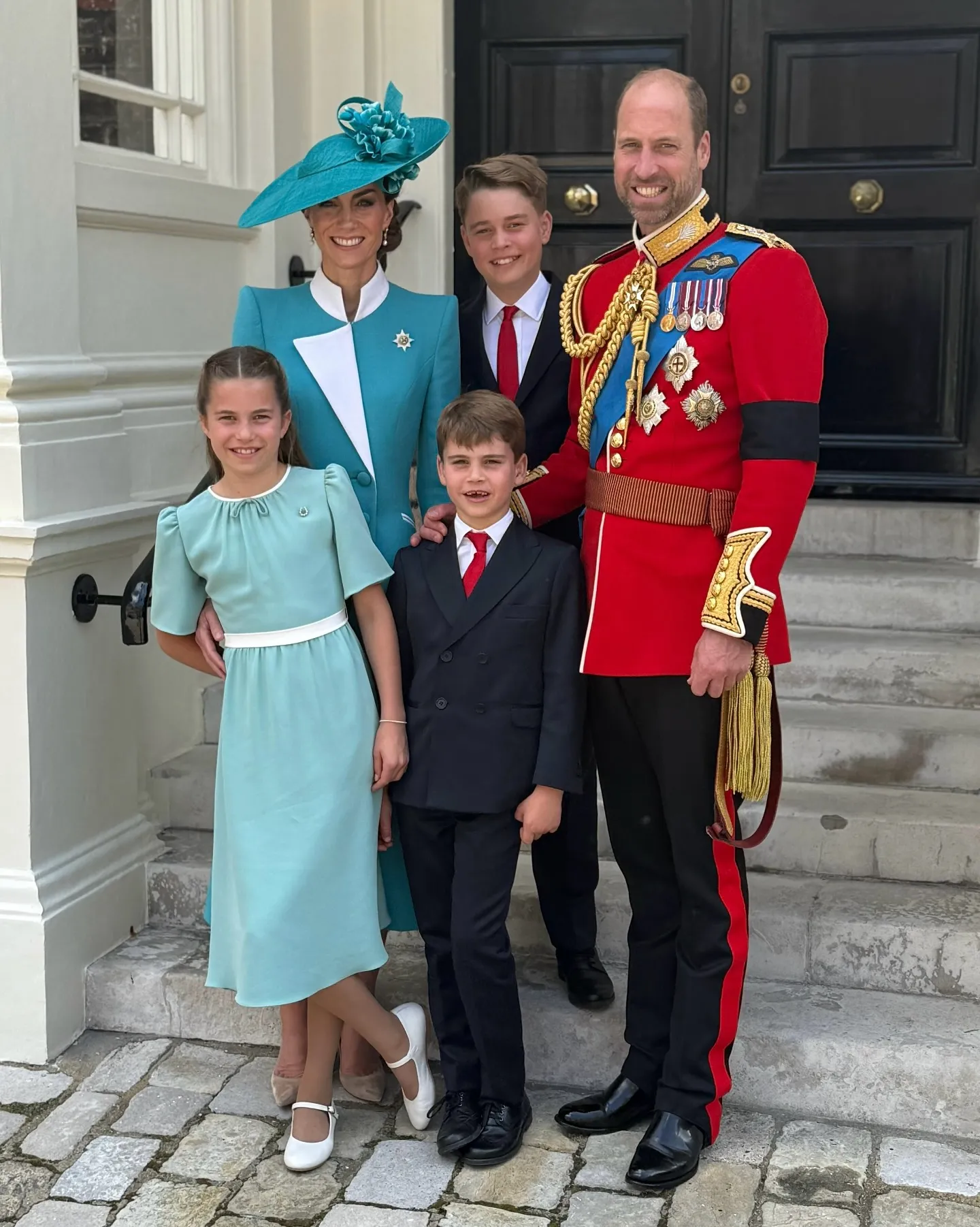 Prince William, Kate Middleton, and their children George, Charlotte, and Louis smiling for a photo.