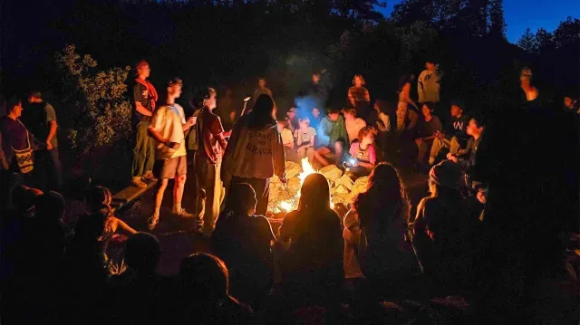 Prospect Sierra students sit around a campfire at Camp Tawonga.