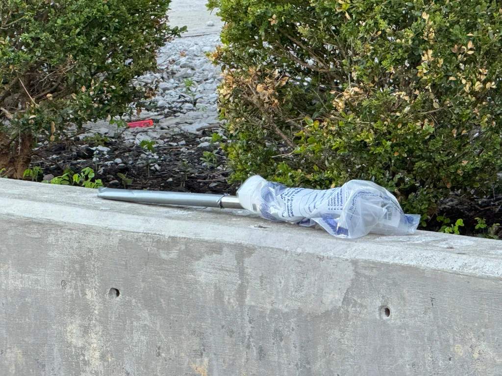 A long silver knife, wrapped in a clear plastic evidence bag, rests on a concrete ledge.