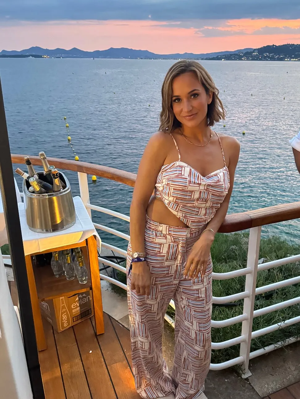 Dianna Russini posing in a two-piece outfit on a boat at sunset.