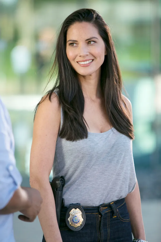 Olivia Munn as a police officer with a badge and gun in 