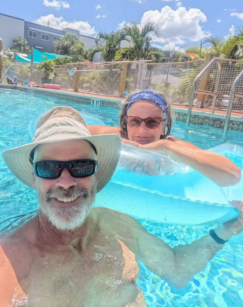 Two people in a swimming pool on a sunny day.