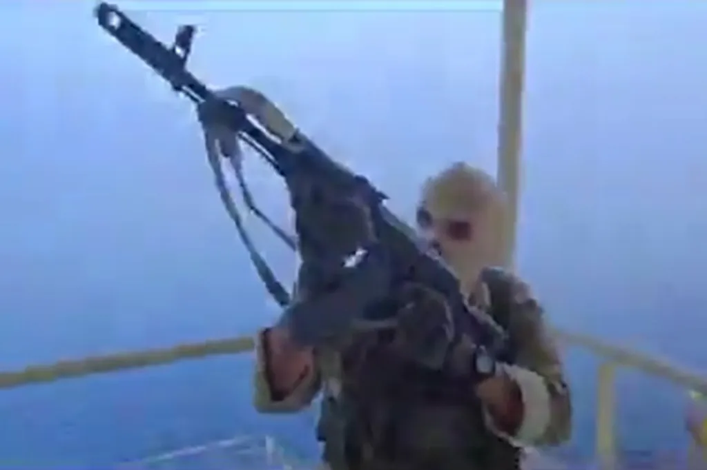 Soldier in military fatigues holding a rifle on a ship.